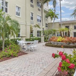 A serene courtyard with palm trees and outdoor seating alongside a well-maintained garden.