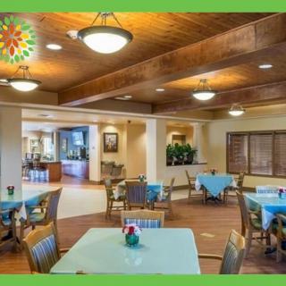 A well-lit dining area with neatly arranged tables and chairs, featuring warm wooden accents and decorative lighting.