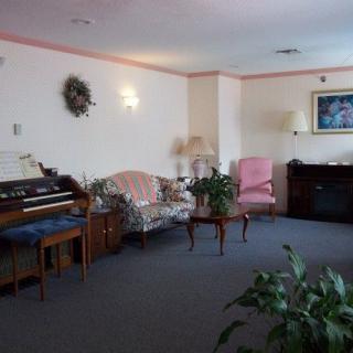 A cozy living room with a sofa, armchair, piano, and decorative plants.