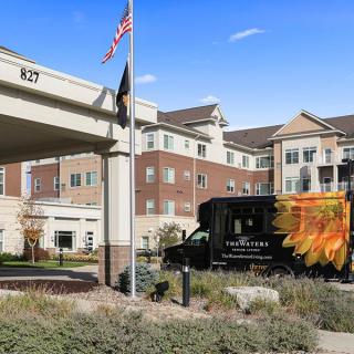 A delivery truck parked outside a residential or commercial building with an American flag flying nearby.