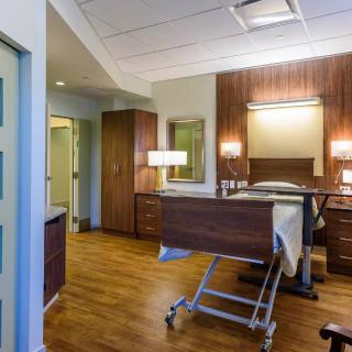 A well-furnished hospital room with a bed and wooden interior elements.