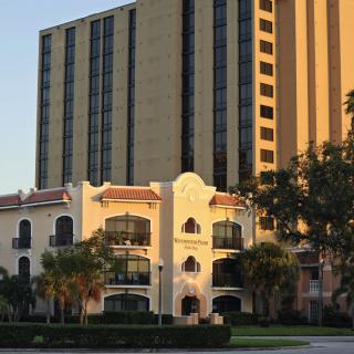 A high-rise hotel building with a classic facade at sunset, surrounded by trees.
