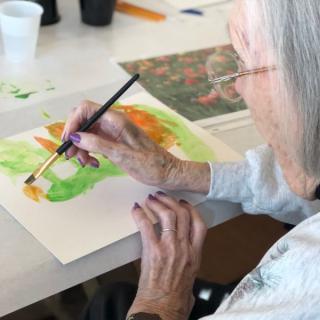 An elderly person engaged in watercolor painting as a creative hobby.