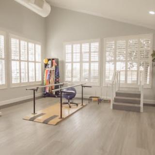 A bright and airy modern workspace featuring a minimalist design with large windows and wooden flooring.