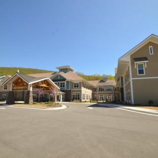 A modern building with a spacious entrance and driveway on a sunny day.