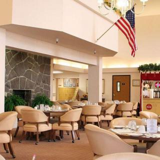Spacious dining area with tables and chairs, featuring an American flag and warm decor.