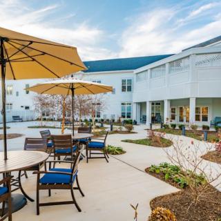 A well-maintained outdoor patio area with seating arrangements and umbrellas, located beside a building.