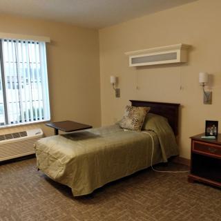 A simple and tidy bedroom with a single bed and a window letting in natural light.