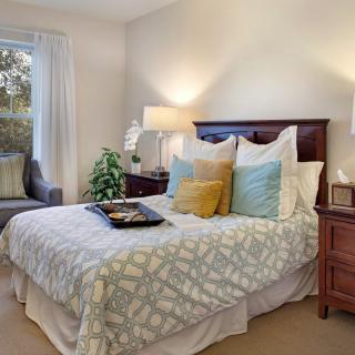 A cozy bedroom with a neatly made bed, soft pillows, and warm lighting.