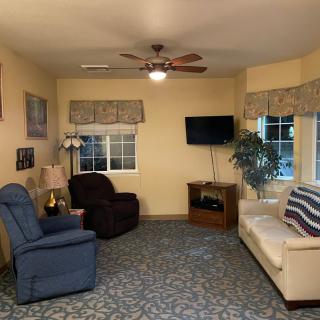 A cozy living room with a sofa, armchairs, and a television mounted on the wall.