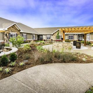 A spacious courtyard with landscaped gardens and a modern building in the background.