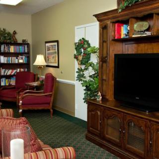 A cozy living room with a television, bookshelf, and comfortable seating.