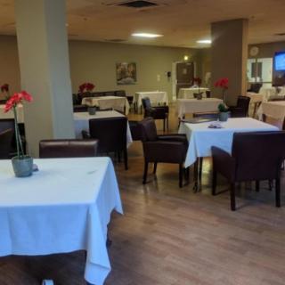 An empty restaurant dining area with tables covered in white tablecloths.