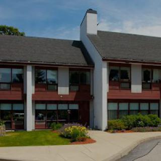 A two-story building with a landscaped front and a clear blue sky.