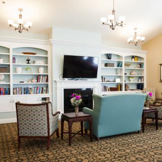 A cozy living room with a seating area, bookshelves, and a television.
