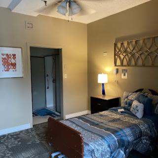 Cozy bedroom with a decorated bed, nightstand, and artwork on the walls.
