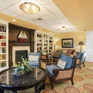 A cozy living room with comfortable chairs, a fireplace, and bookshelves filled with books.