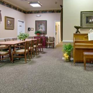 A room with chairs and tables, a piano, and decorative elements on the walls.