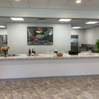 A modern reception area with a counter, featuring flowers and artwork.