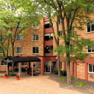 A charming brick apartment building surrounded by lush trees.