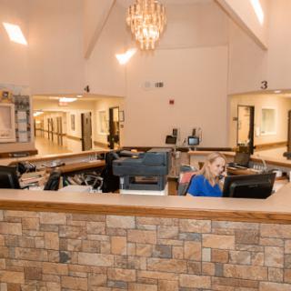 A modern reception area featuring a stylish chandelier and a dedicated staff member at the front desk.