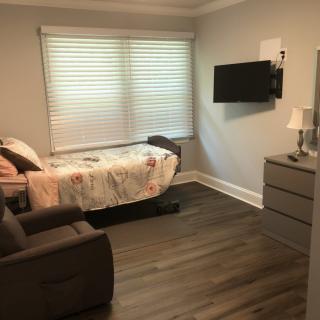 A cozy bedroom with a single bed, wall-mounted TV, and armchair.