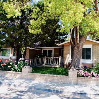 A charming residential house surrounded by lush greenery and vibrant flowers.