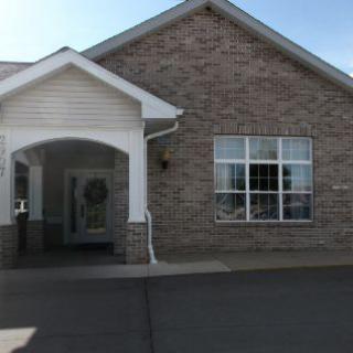 A brick building with a covered entrance and large windows.