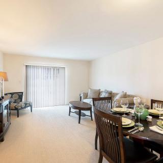 A spacious living room combined with a dining area, featuring elegant furniture and bright lighting.