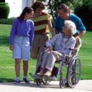 A family enjoying time outdoors with an elderly person in a wheelchair.