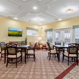 A cozy dining area with multiple tables and chairs, adorned with a patterned carpet and bright lighting.