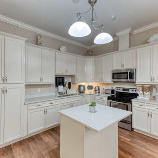 A modern kitchen with white cabinets, a central island, and stainless steel appliances.