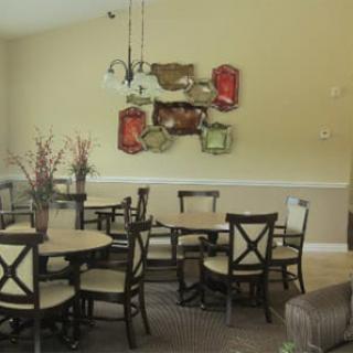 A dining area with multiple tables and chairs, decorated with wall art and hanging lights.