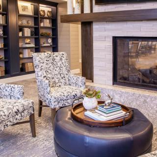 A cozy living room with armchairs, a fireplace, and bookshelves.