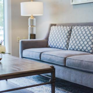 A cozy living room with a grey sofa, patterned cushions, and a wooden coffee table.