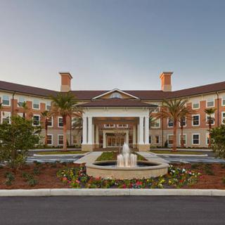 A grand hotel entrance with a central fountain, surrounded by landscaped gardens.
