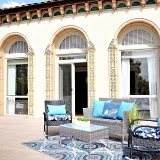 A stylish outdoor patio with modern furniture and decorative cushions set against an elegant building facade.