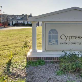 A sign for Cypress skilled nursing facility in front of a building in a grassy area.