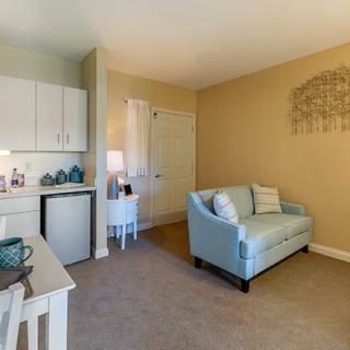 A cozy living area featuring a light blue couch, a small kitchenette, and beige walls.
