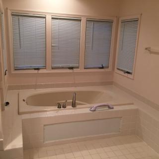 A bathroom featuring a built-in bathtub with surrounding windows and closed blinds.