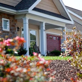 A suburban house with a landscaped front yard featuring various plants and flowers.