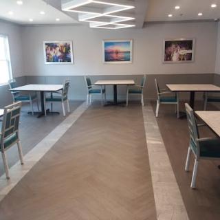 A spacious and modern dining area featuring well-arranged tables and artwork on the walls.