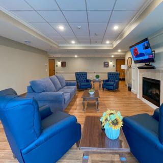 A cozy living room with blue furniture and a mounted television near the fireplace.