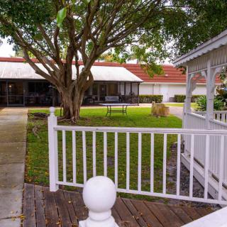 A tranquil garden view with a gazebo, lush greenery, and a white fence.