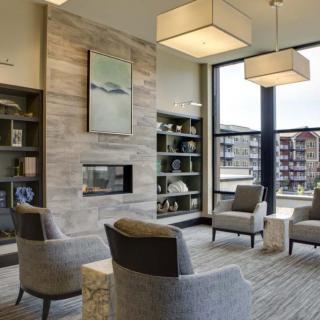 A modern living room with a cozy seating area around a fireplace, featuring contemporary furniture and decorative shelves.
