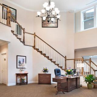 A spacious office interior with a desk, staircase, and chandelier.