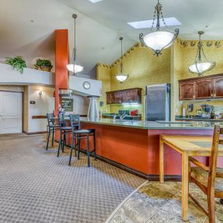 A spacious kitchen with a large counter, bar stools, and modern lighting.