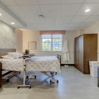 A clean and tidy hospital room with a bed and furniture.