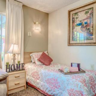 A cozy bedroom with a decorated single bed, wall art, and a bedside lamp.