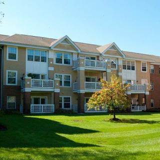 An apartment building with balconies and a well-maintained lawn on a sunny day.